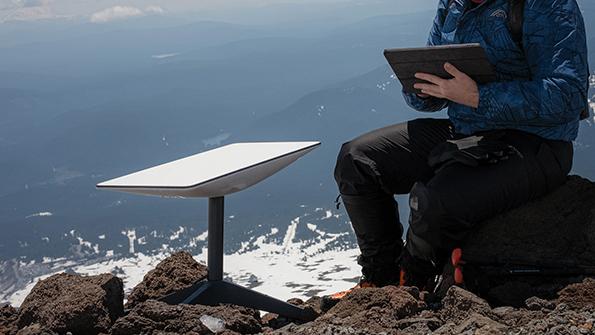 Person sitting with tablet next to Starlink terminal